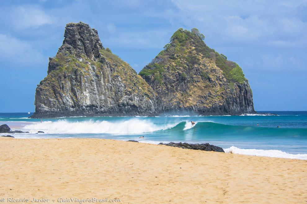 Imagem de surfistas no mar em Fernando de Noronha.